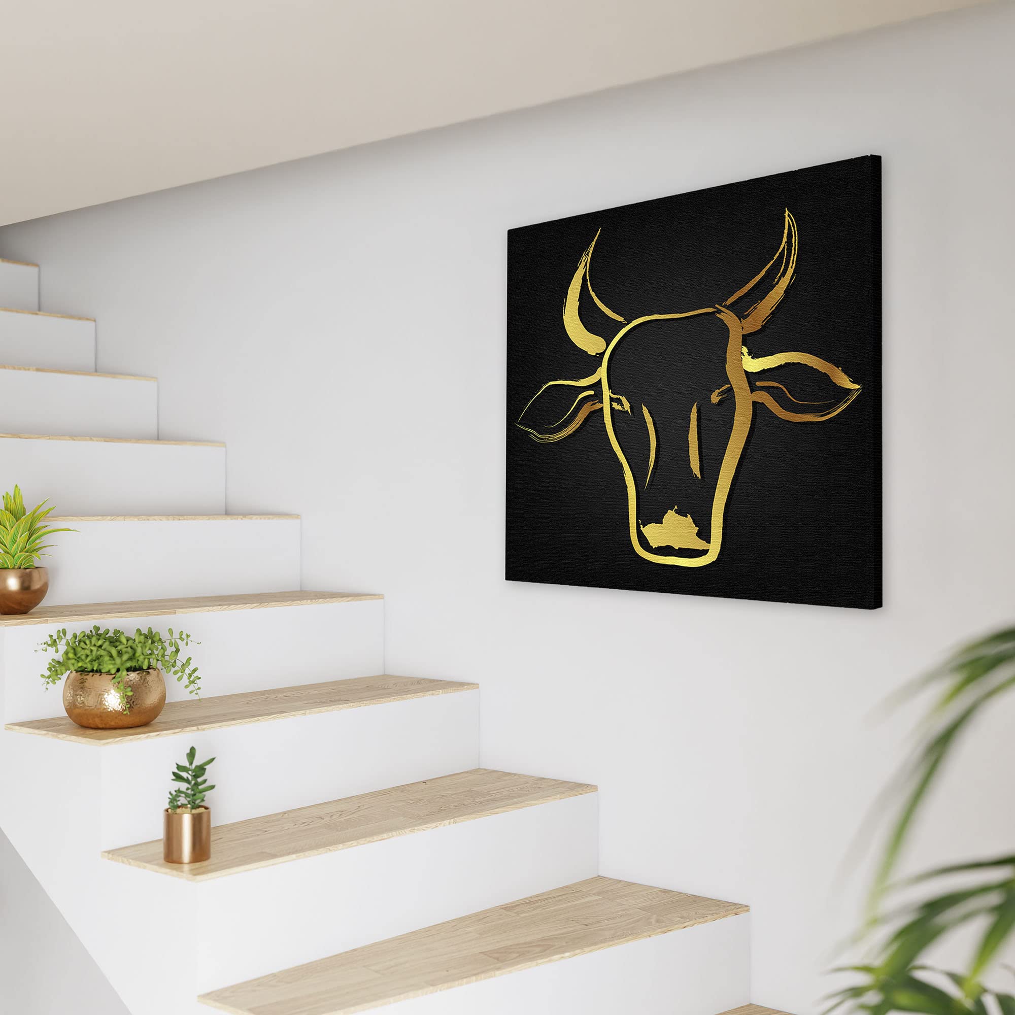 Black and gold abstract cow art with sleek brushstroke design on square canvas displayed on white wall near staircase