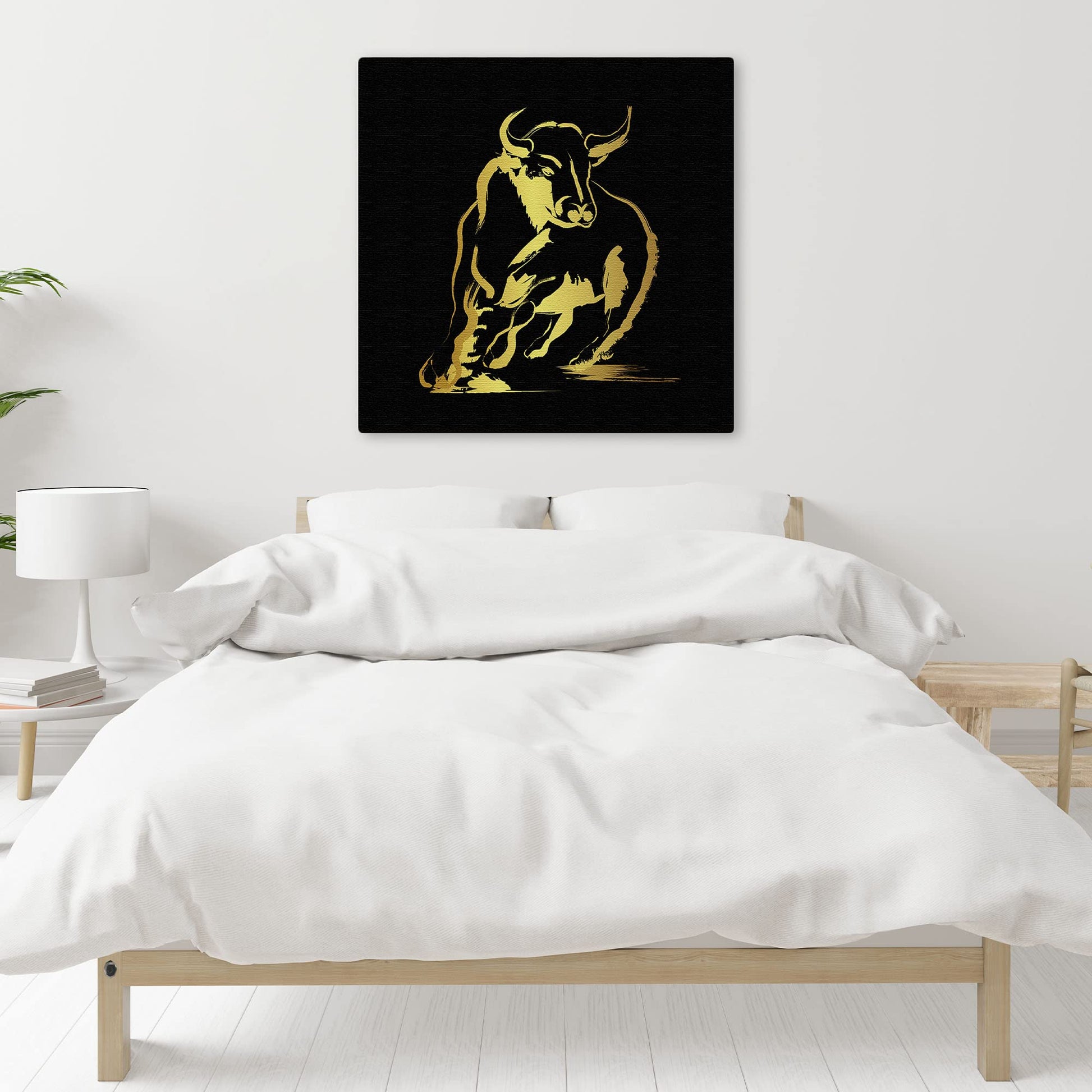Abstract black and gold bull art with bold brushstroke design on square canvas displayed above bed in minimalist bedroom