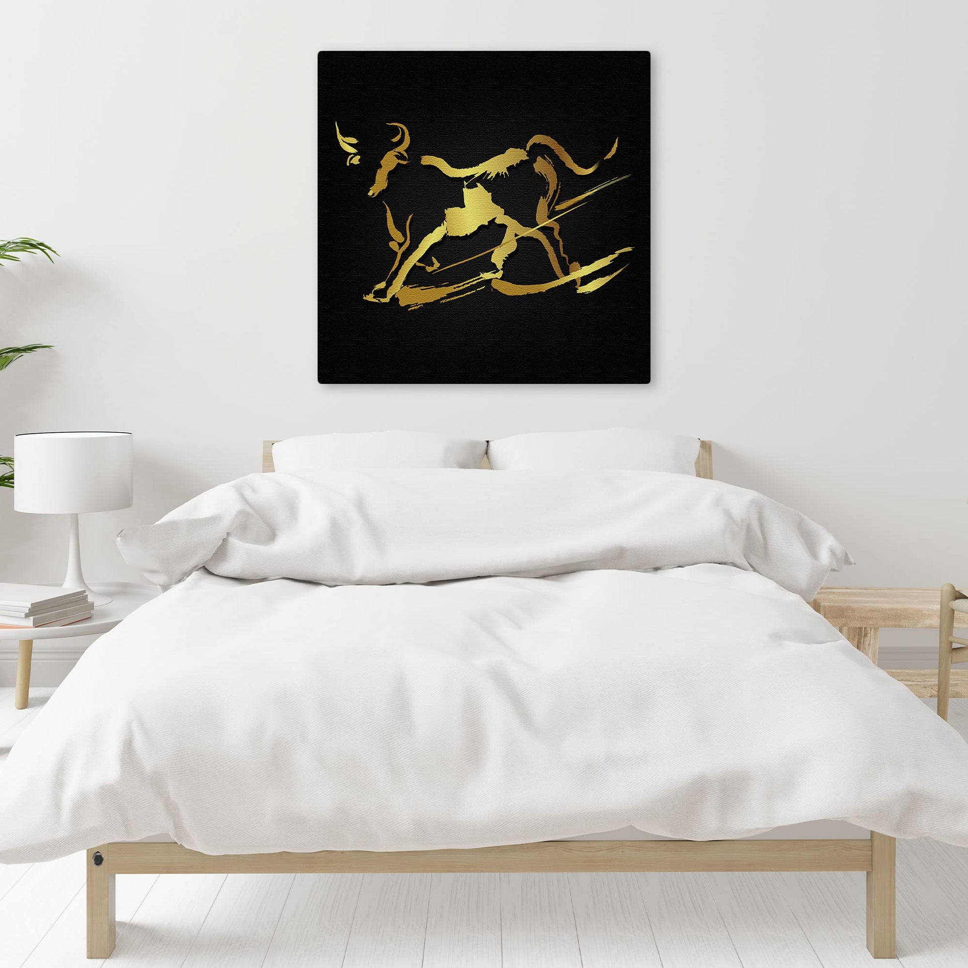 Abstract black and gold bull wall art with sleek minimalist design on square canvas above bed in modern bedroom