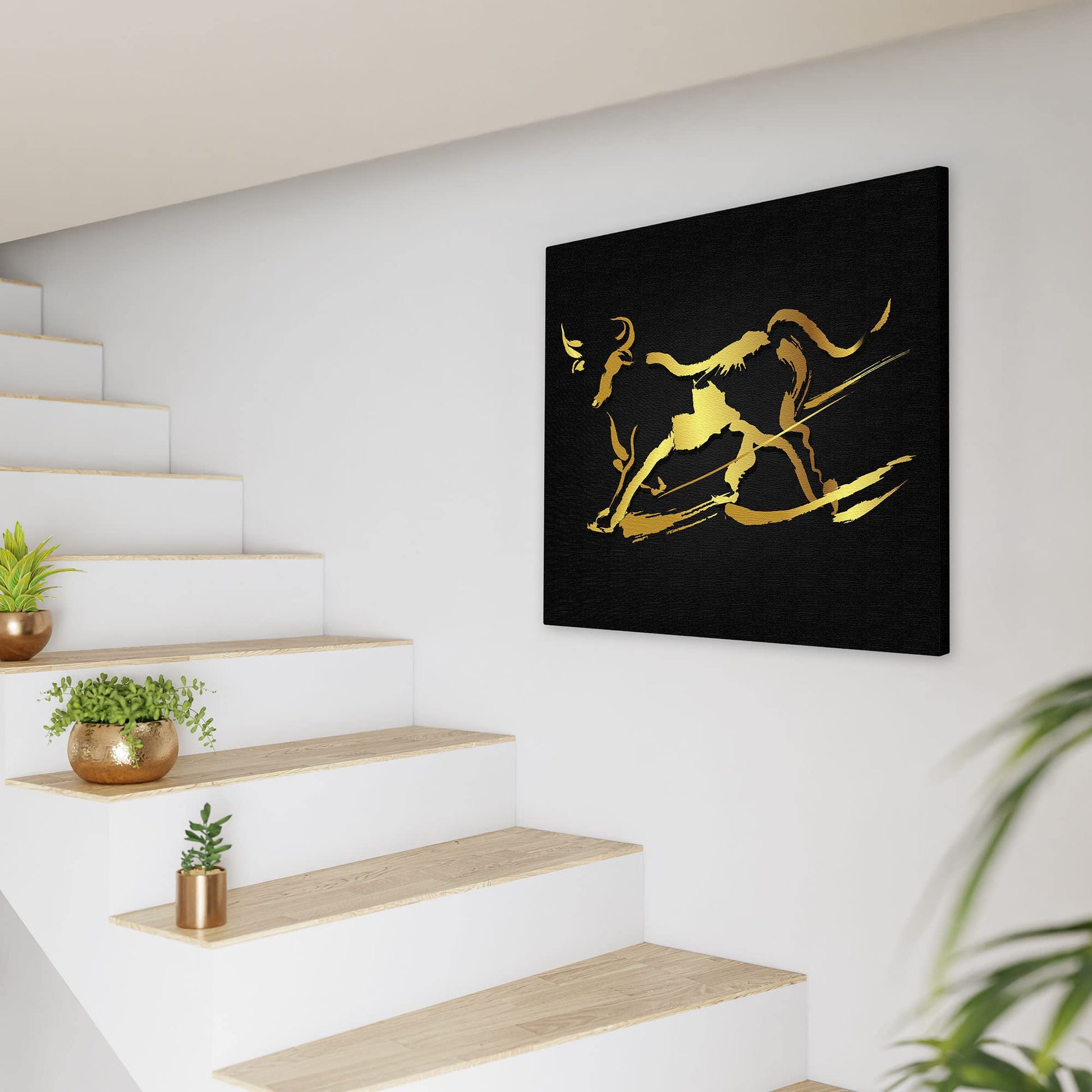 Abstract black and gold bull wall art with fluid brushstroke design on square canvas displayed on white wall by modern staircase