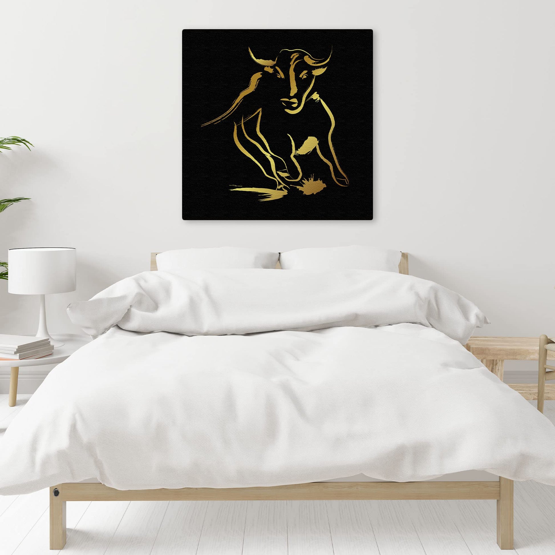 Abstract black and gold bull art with bold brushstroke design on square canvas above modern bed in minimalist bedroom
