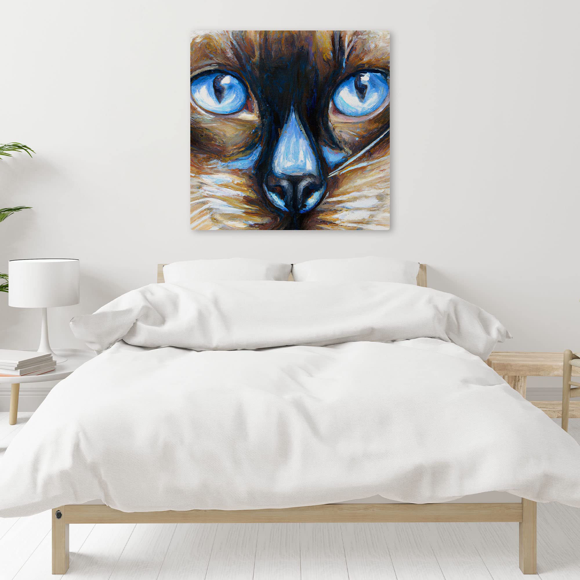 Close-up Siamese cat wall art with intense blue eyes and textured brush strokes on square canvas above white bed in minimalist room