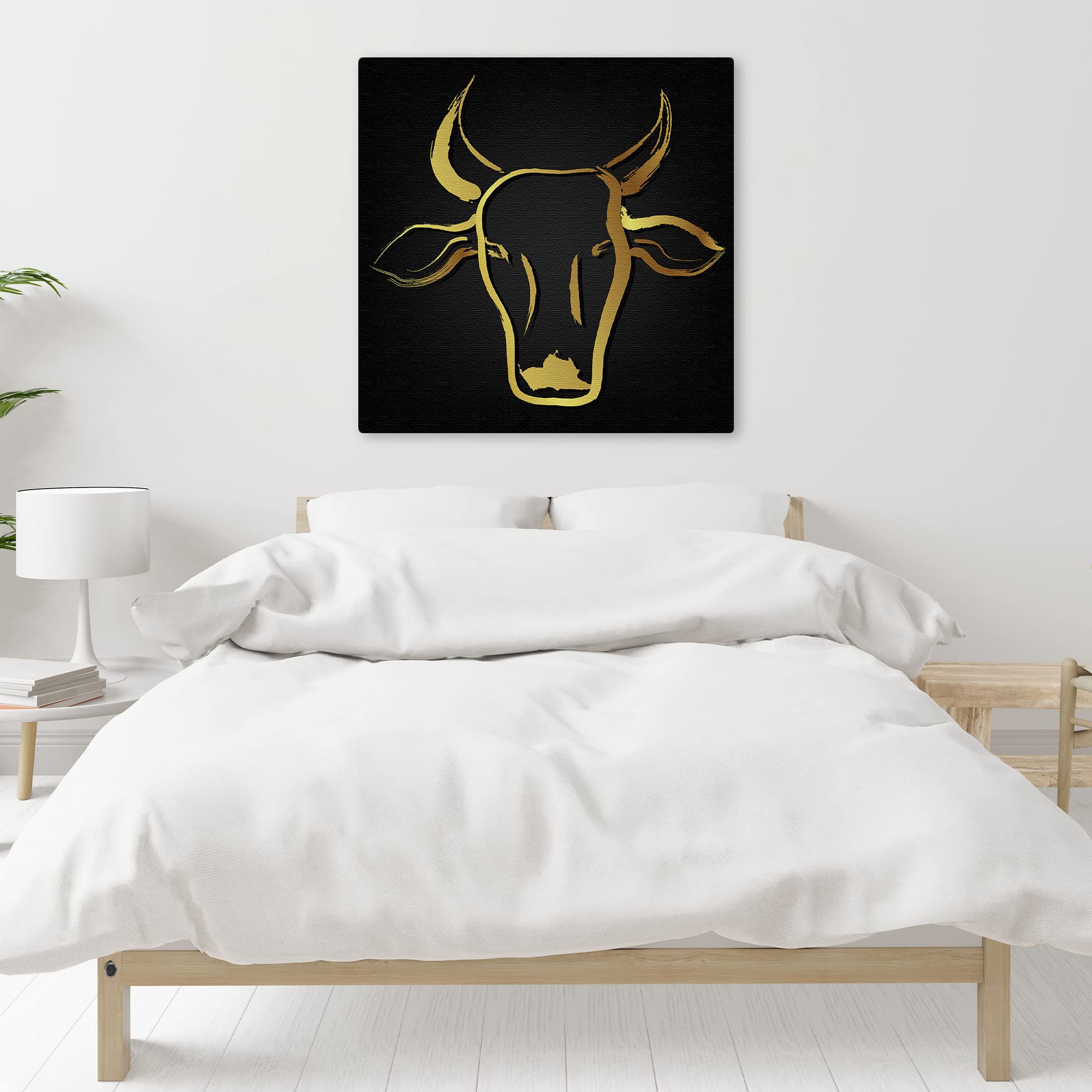 Abstract black and gold cow art with sleek brushstroke design on square canvas displayed above bed in minimalist bedroom