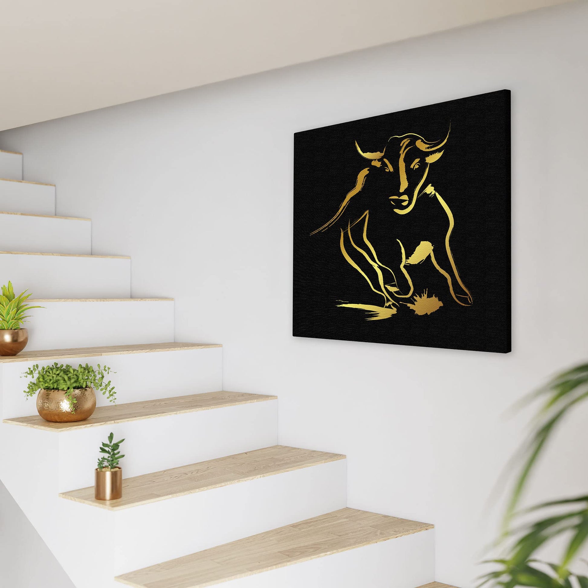 Black and gold abstract bull art with dynamic brushstroke design on square canvas displayed on white wall near modern staircase