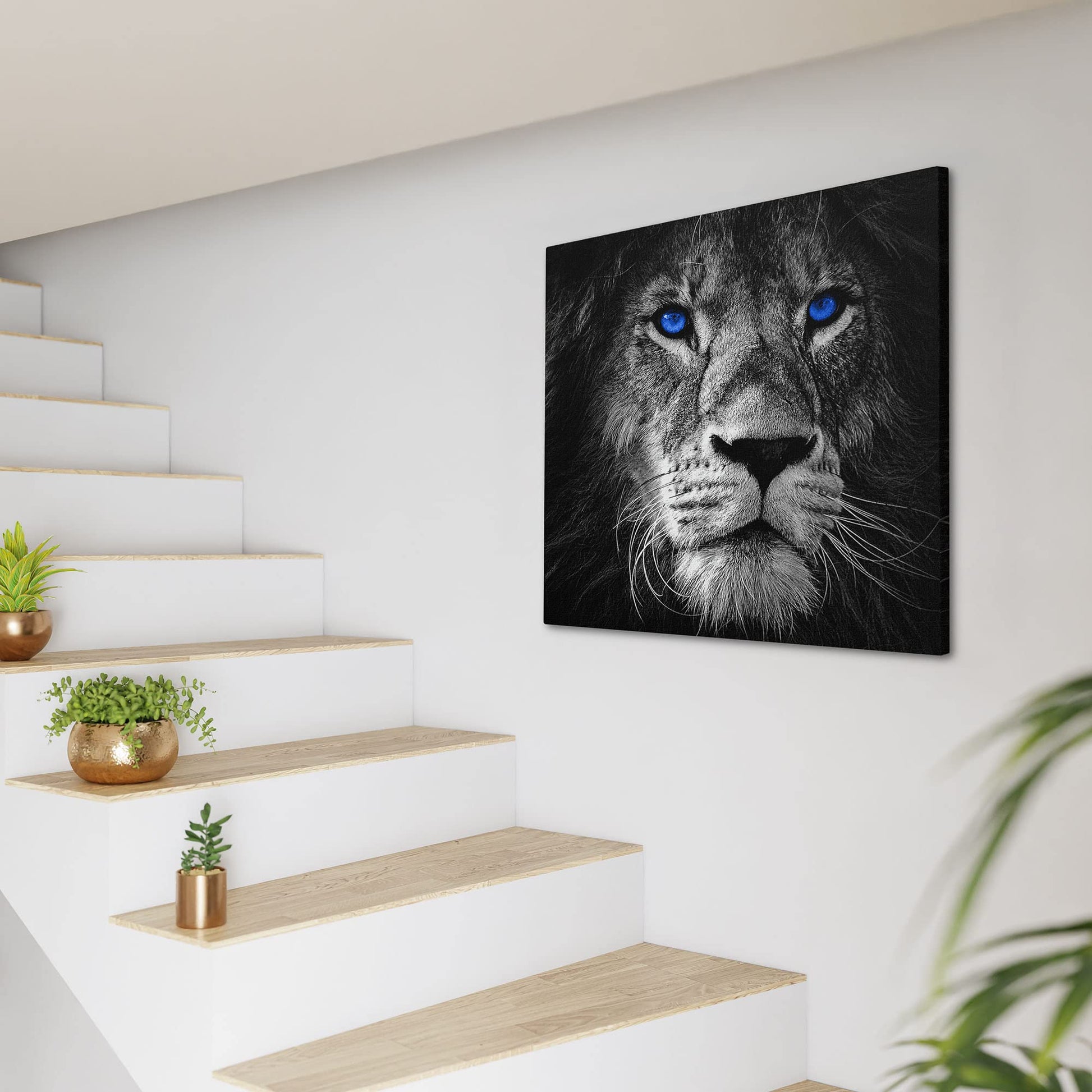 Black and white lion face with vivid blue eyes printed on canvas hanging on white wall by modern staircase